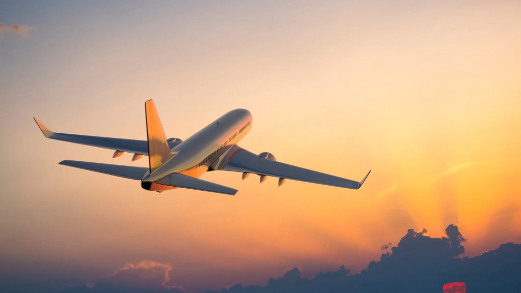 A large plane flying into the sunset.
